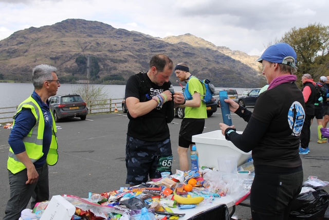 A team of people volunteering at a race aid station to help a runner. 